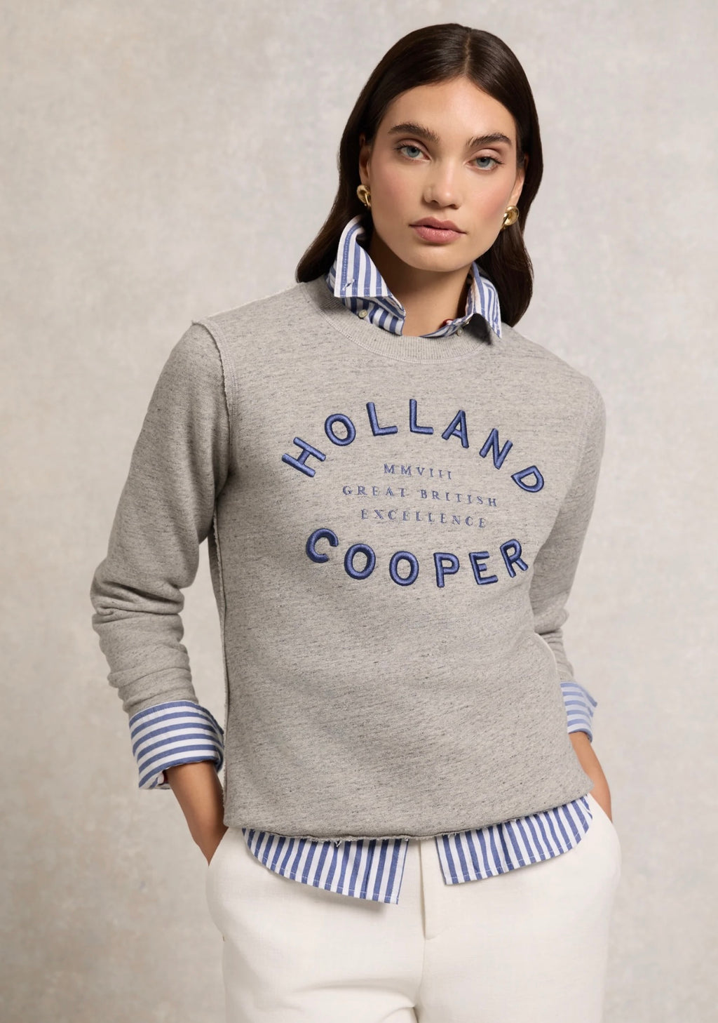Woman wearing a gray sweater with 'Holland Cooper' branding on a beige background