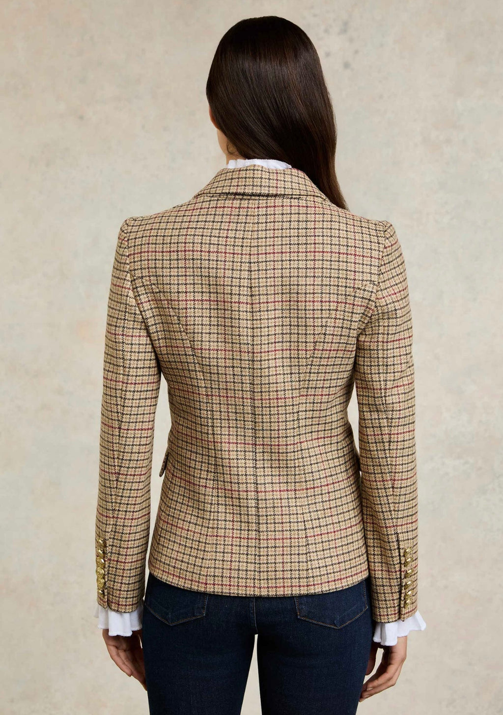 Person wearing a beige checkered blazer against a neutral background