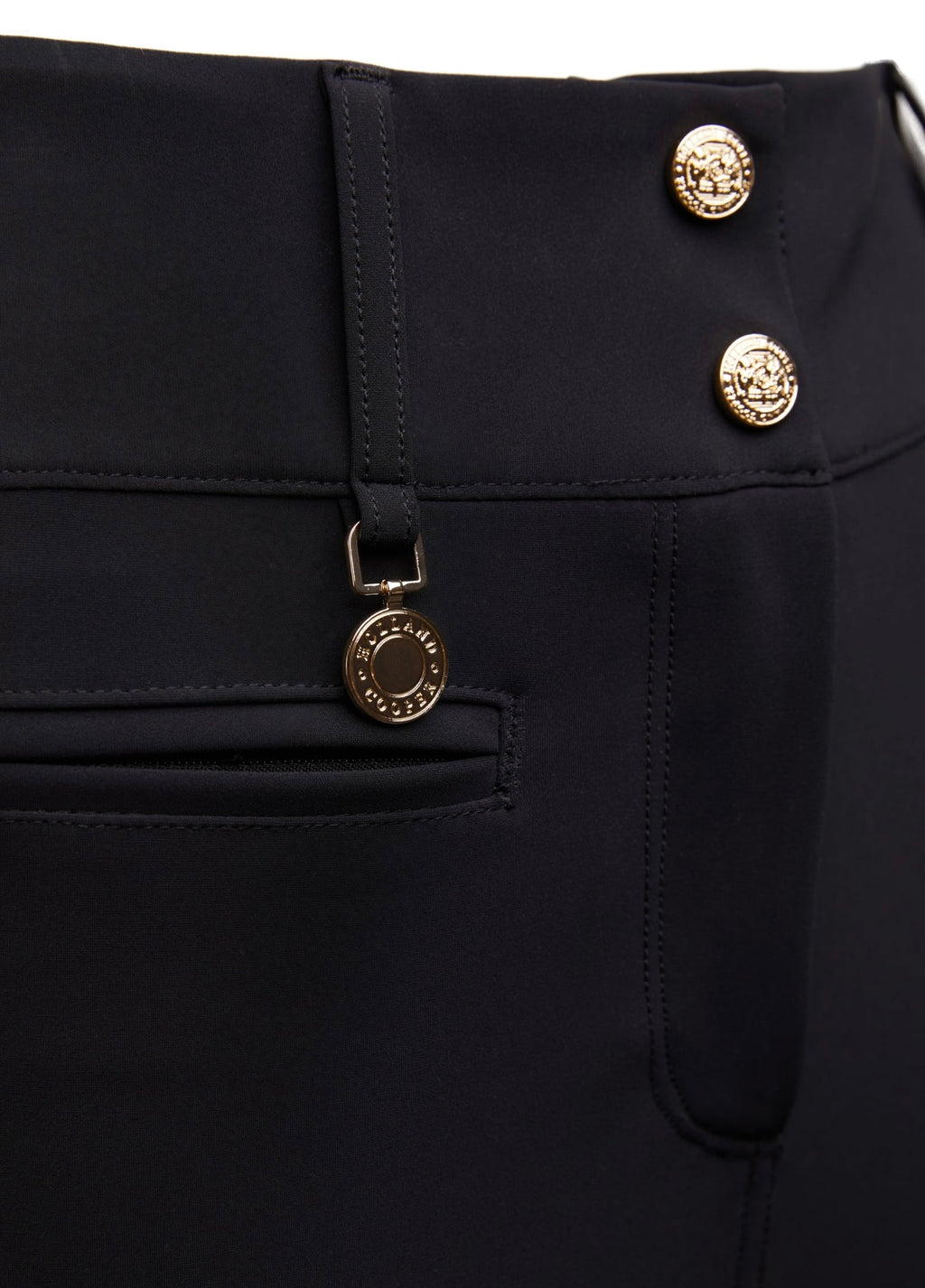 Close-up of a black garment with gold buttons featuring a brand logo.
