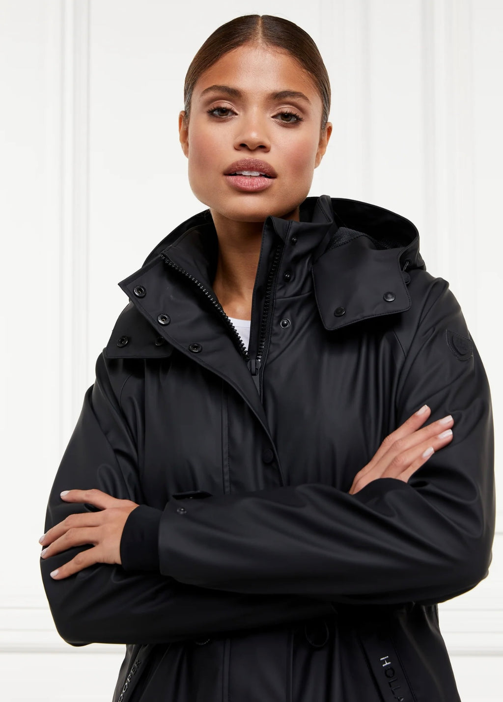 Woman wearing a black coat with a hood against a white background