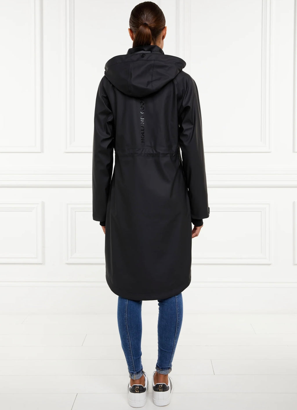 Person wearing a long black coat with a hood on a white background