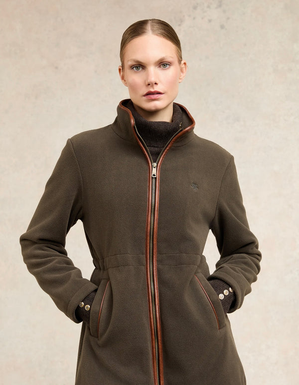 Woman wearing a brown coat with a zipper on a beige background
