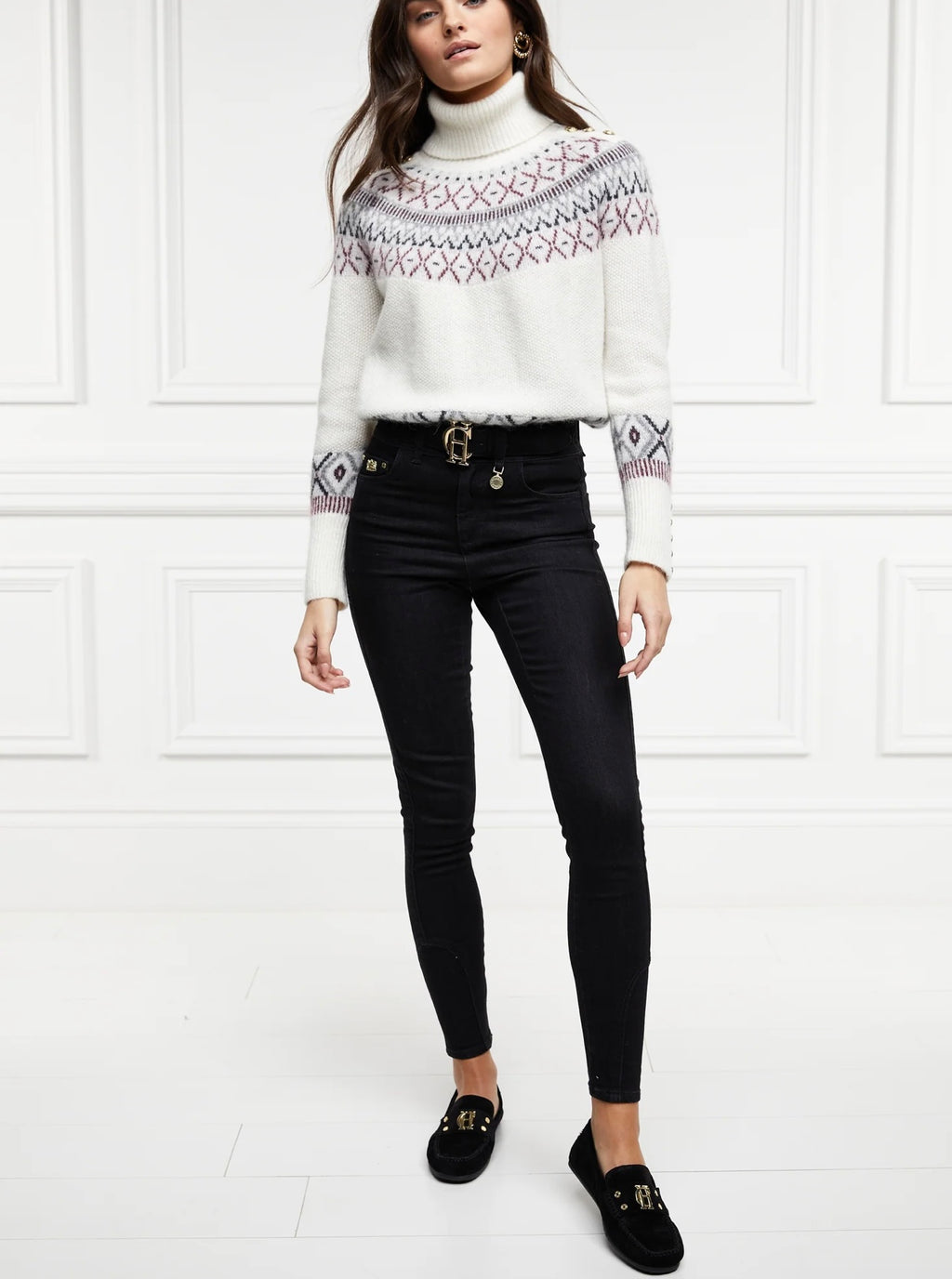 Woman wearing a white patterned sweater, black pants, and black shoes on a white background