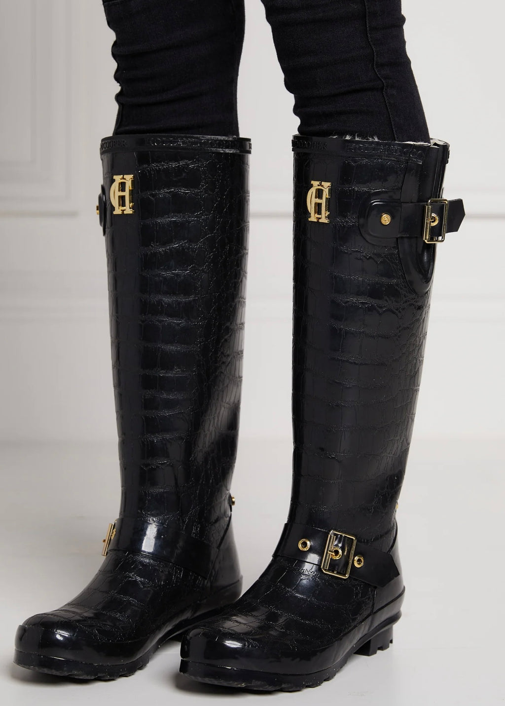 Black knee-high boots with gold buckles on a white background