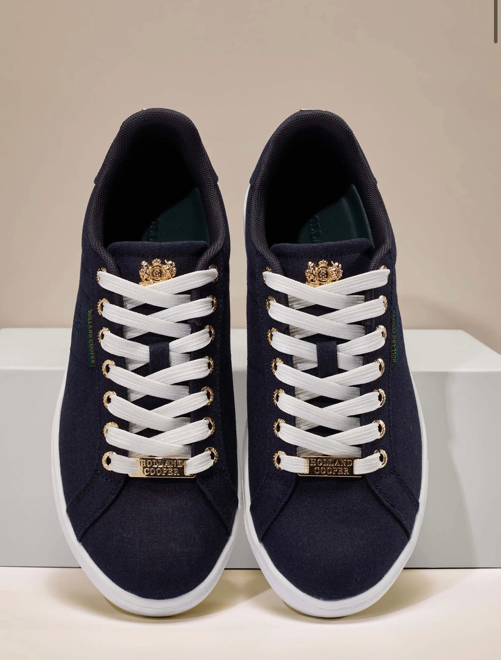 Pair of navy blue sneakers with white laces on a light gray background