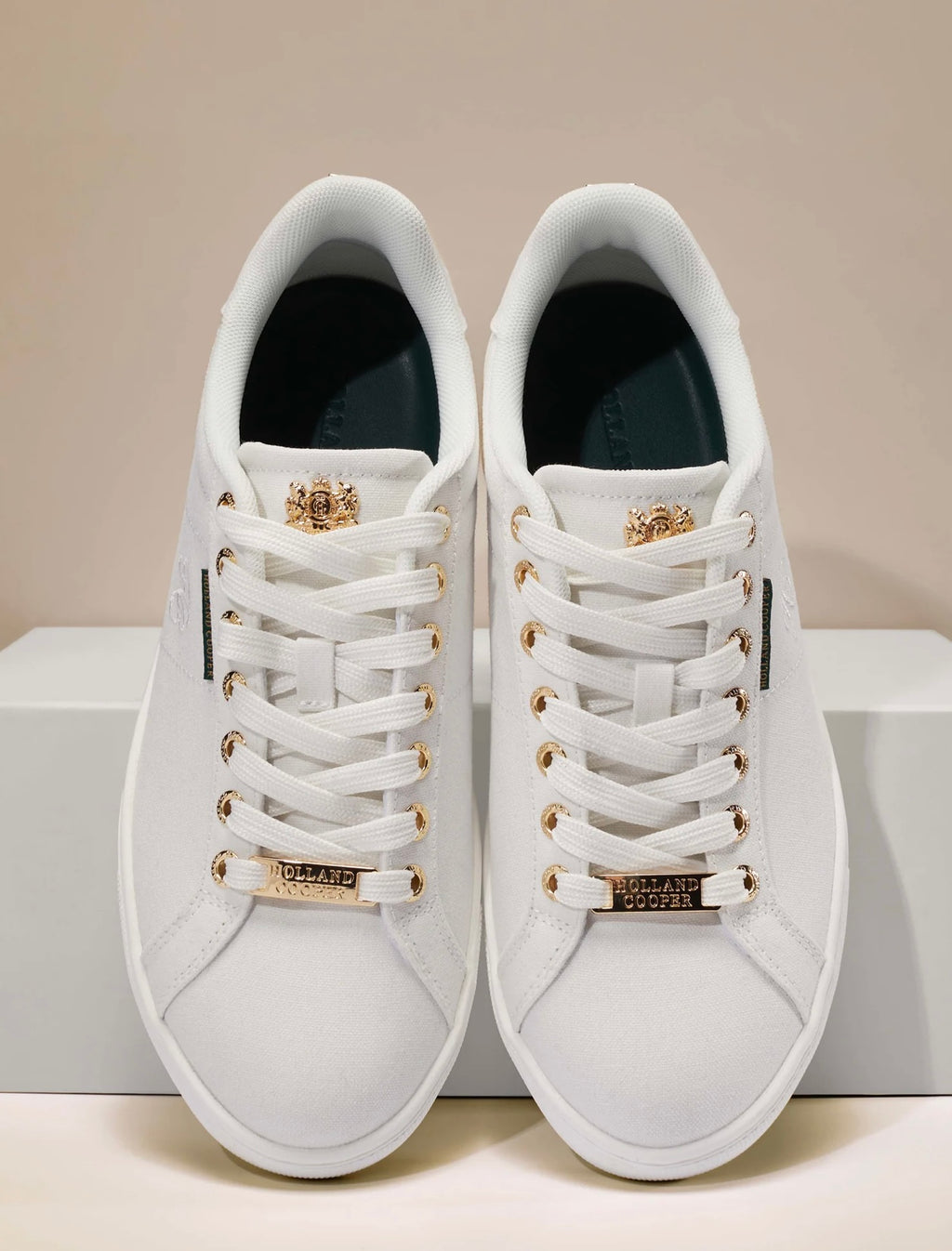 White sneakers with gold accents on a beige background