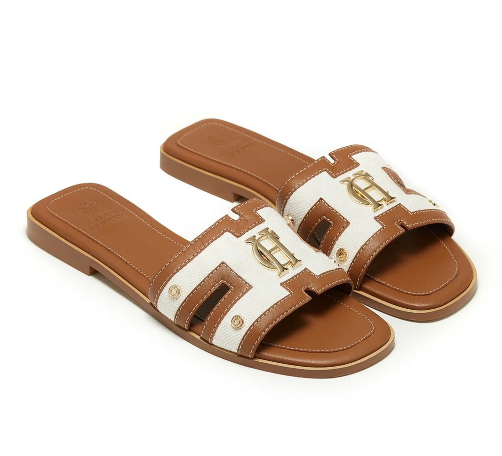 Brown and white sandals with gold logo on a white background