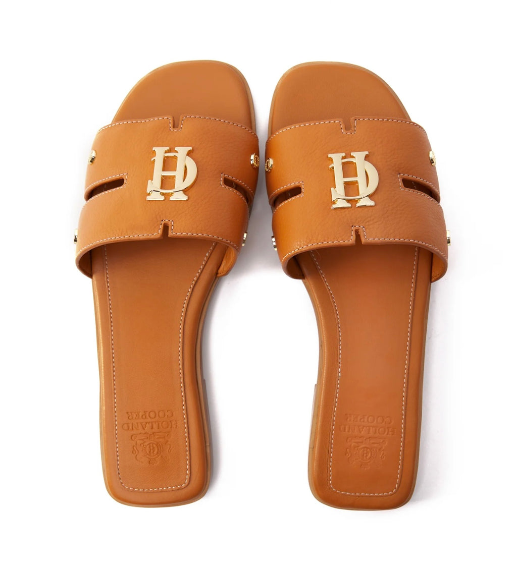 Pair of tan sandals with logo on a white background