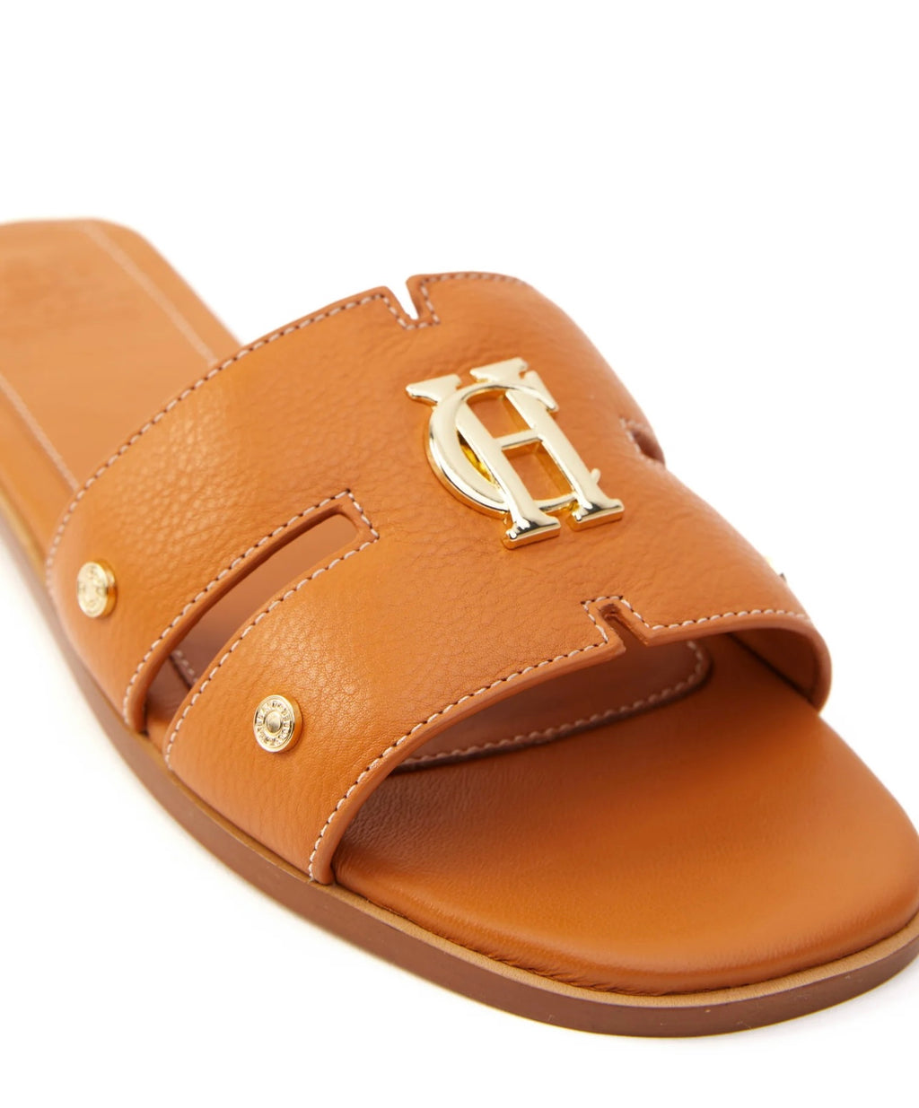Brown sandal with gold logo and embellishments on a white background