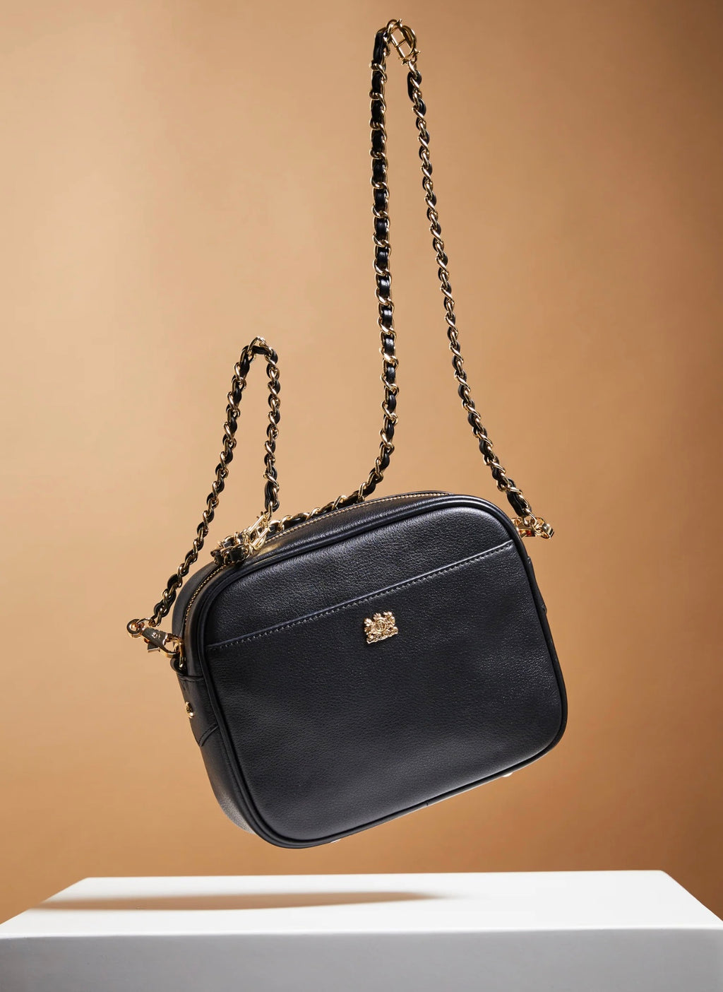 Black handbag with chain strap on a beige background