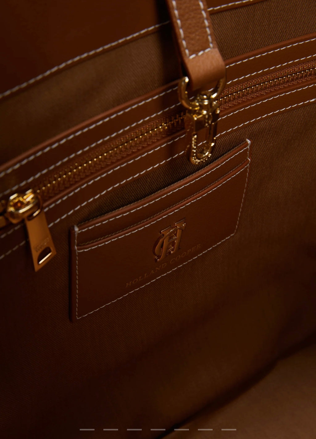 Close-up of a brown leather bag with gold hardware and a visible brand logo.