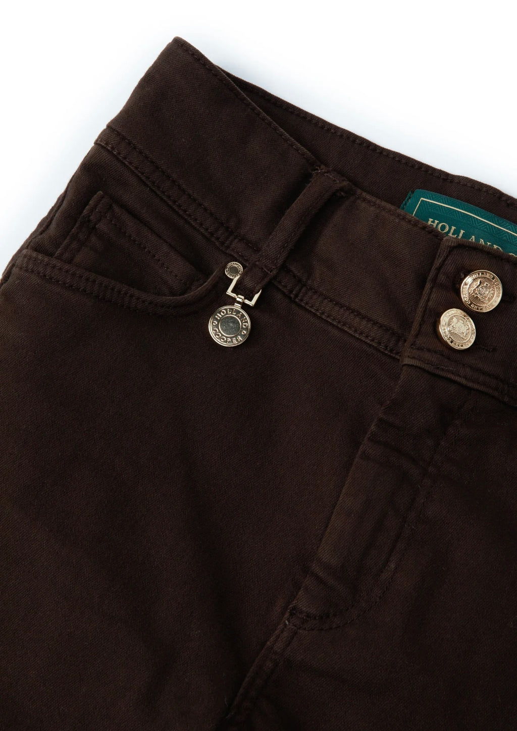 Close-up of dark brown pants with a visible brand label on a white background