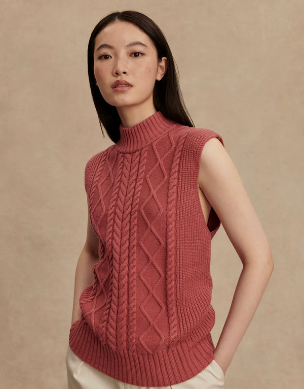 Woman wearing a pink knitted vest against a beige background