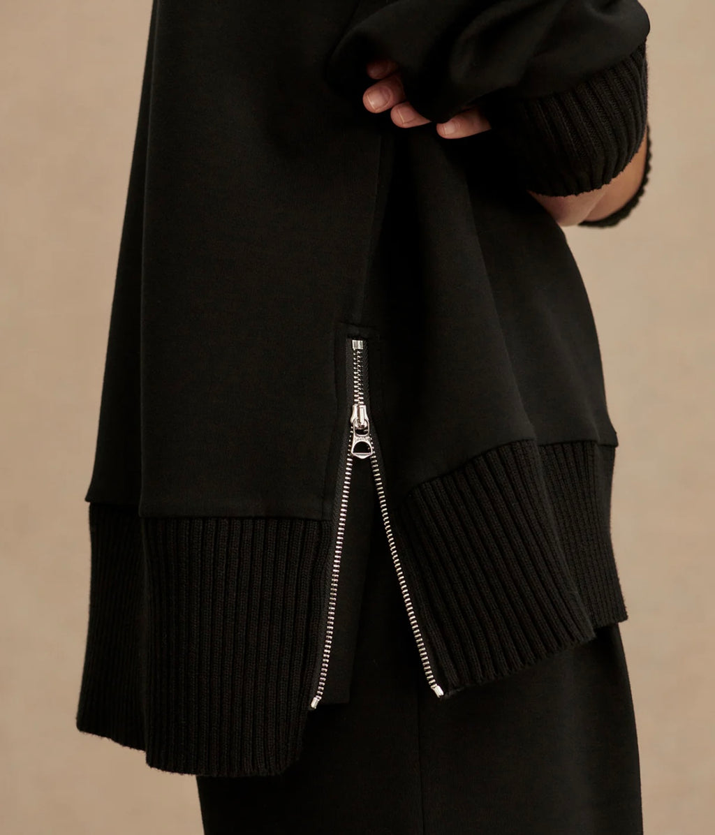 Black layered outfit with a zipper detail on a beige background