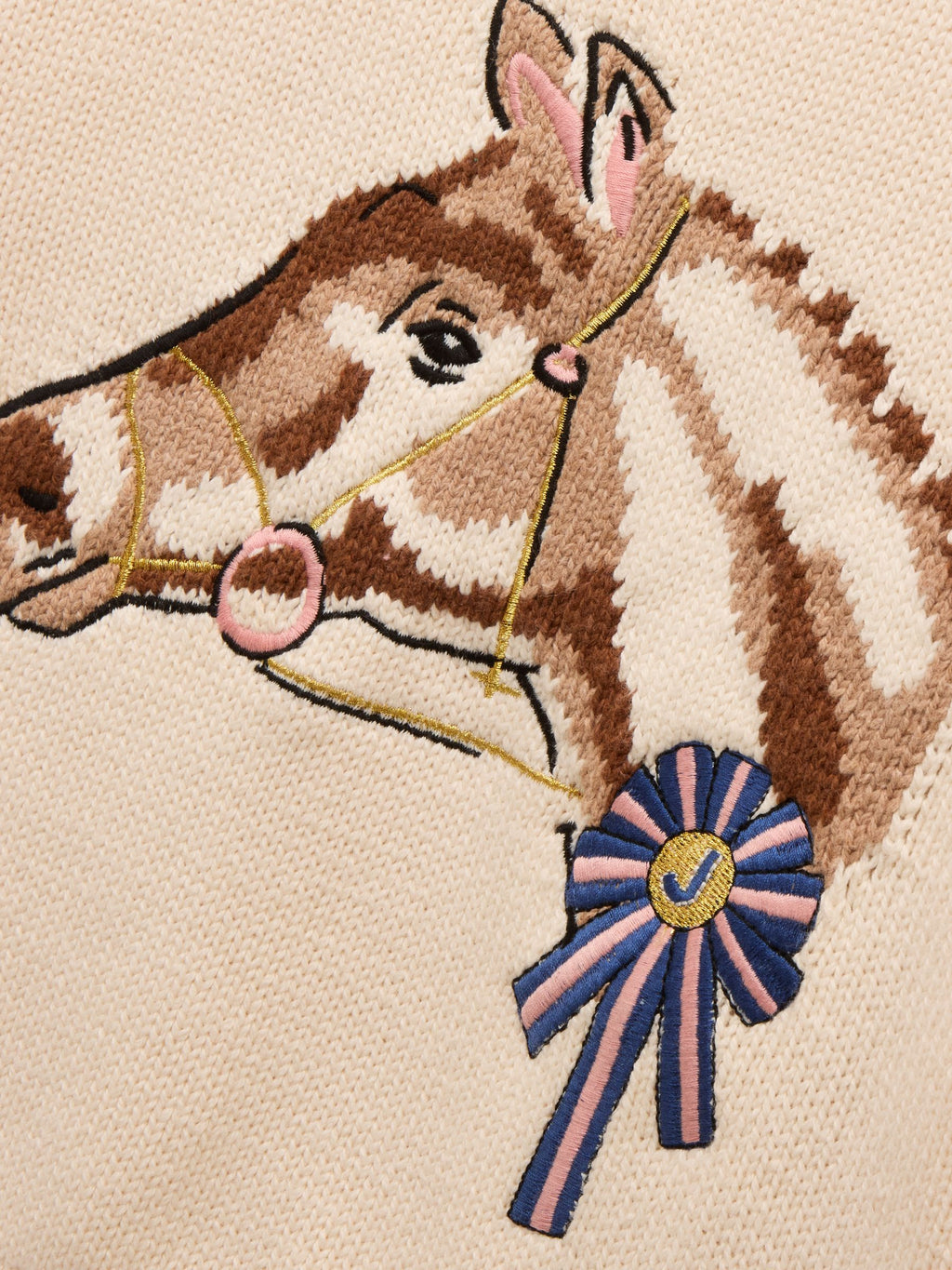 Embroidered design of a horse's head with a blue ribbon on a beige background