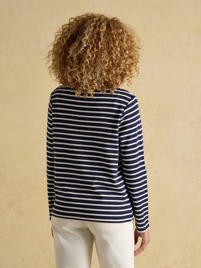 Person wearing a navy and white striped long-sleeve shirt against a beige background