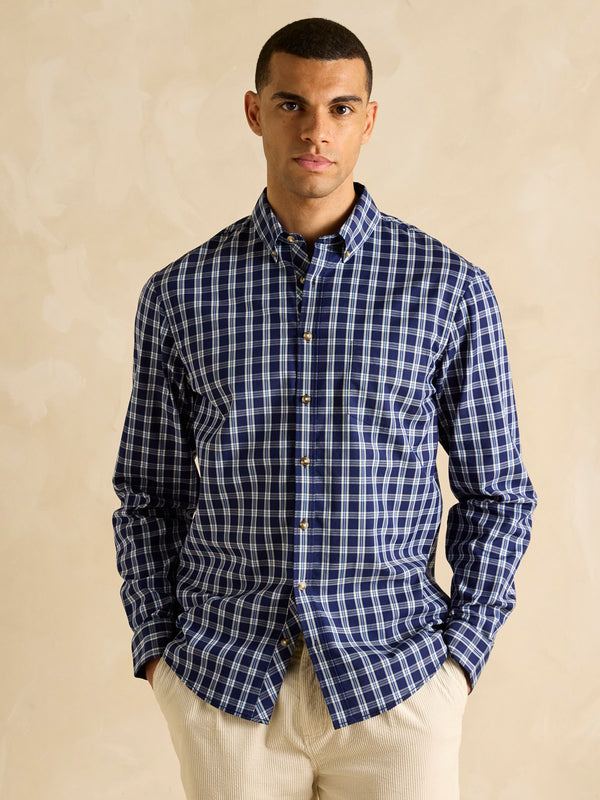 Man wearing a blue checkered shirt against a beige background