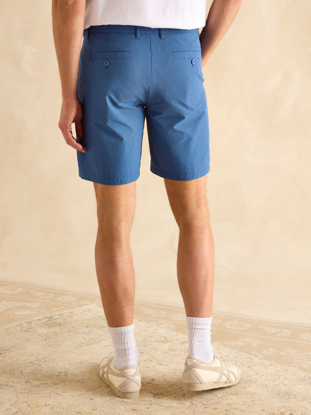Person wearing blue shorts on a beige background