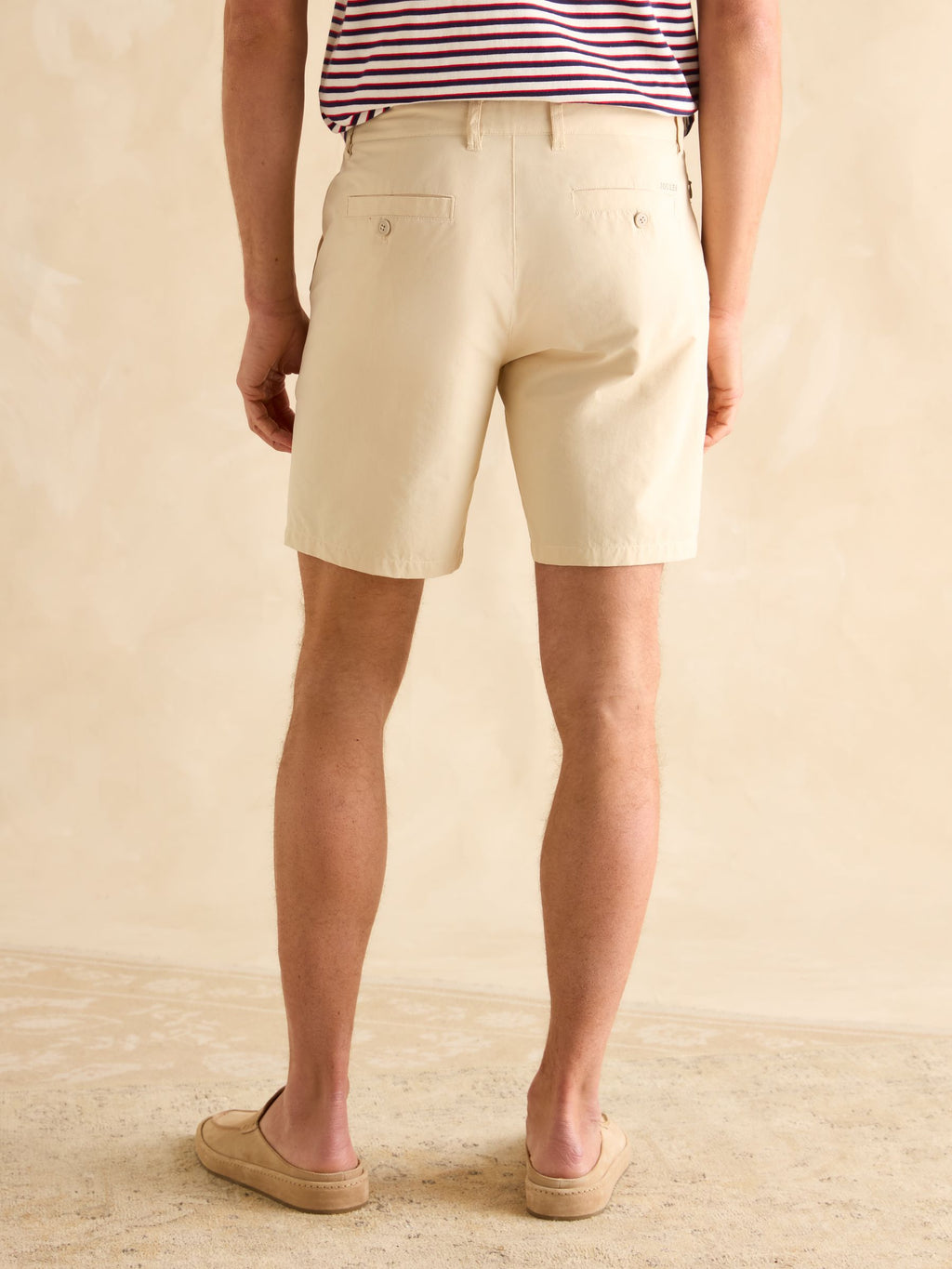Person wearing beige shorts on a neutral background
