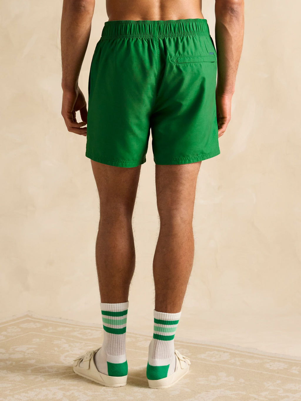 Person wearing green shorts and matching socks on a beige background