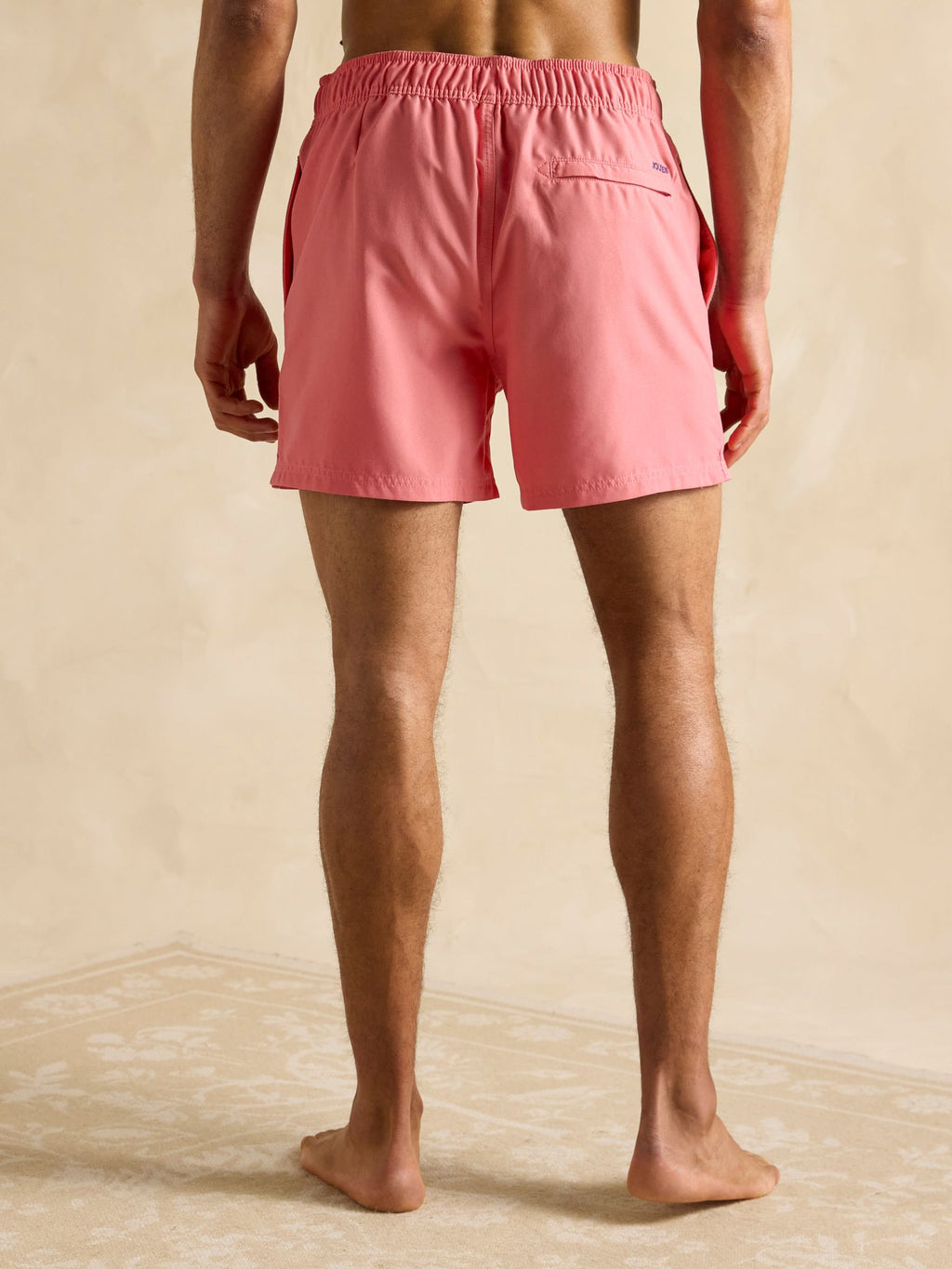 Person wearing pink shorts on a beige background