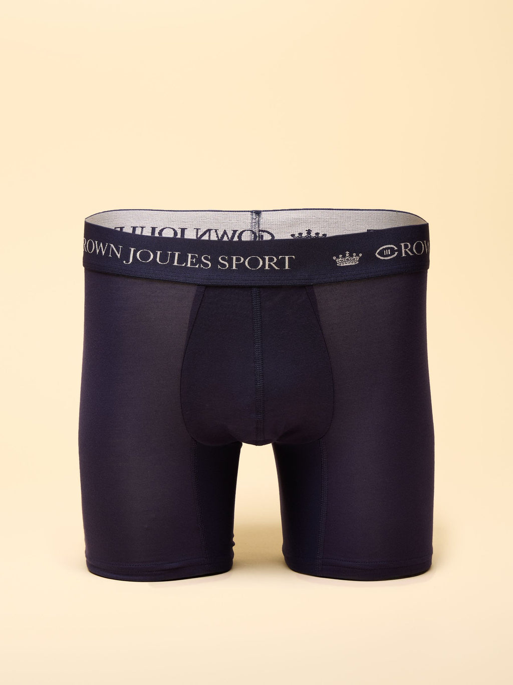 Navy blue boxer briefs with a branded waistband on a beige background