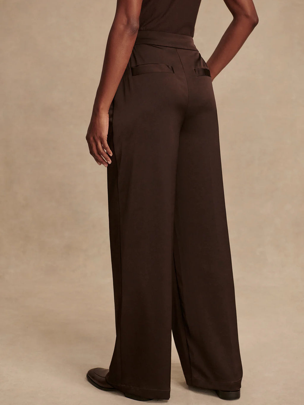 Brown wide-leg pants worn by a person on a beige background