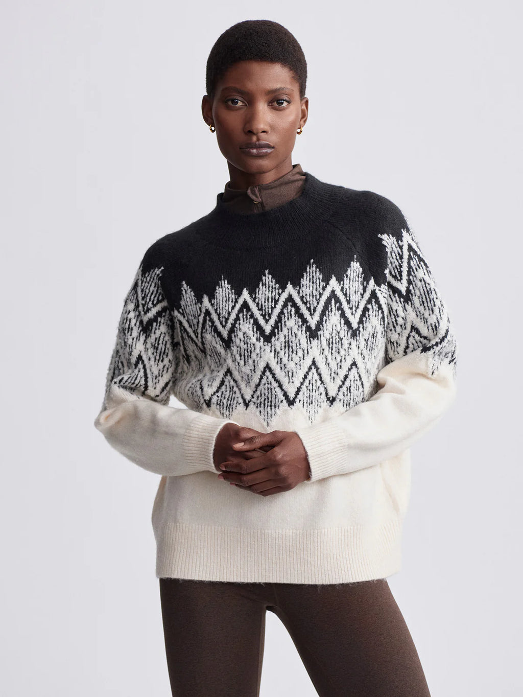 Person wearing a black and white patterned sweater on a plain background
