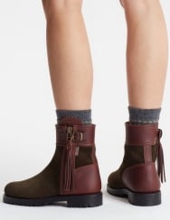 Brown leather boots with tassels worn by a person on a white background