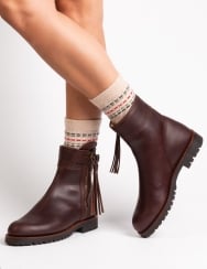 Brown ankle boots with fringes worn by a person on a light gray background