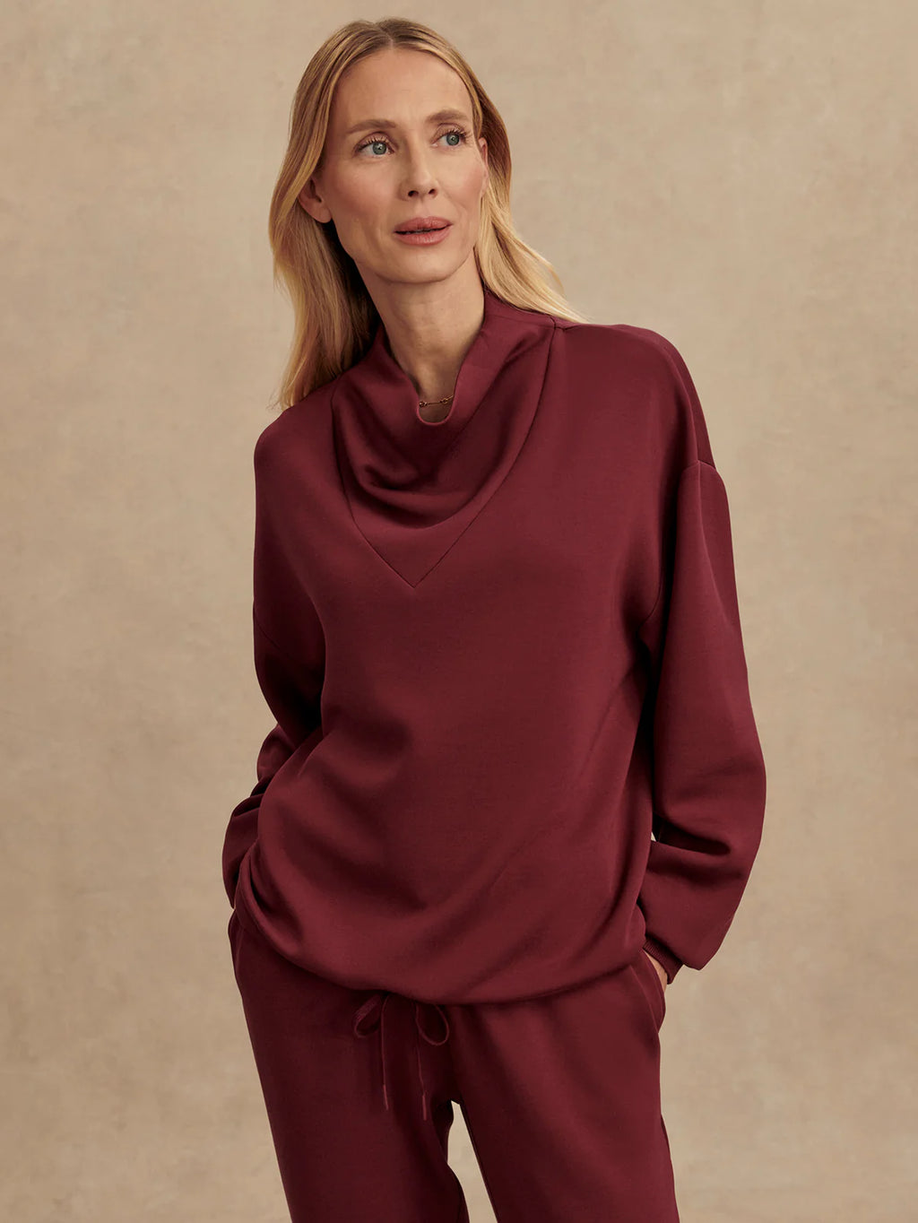 Woman wearing a burgundy outfit against a beige background