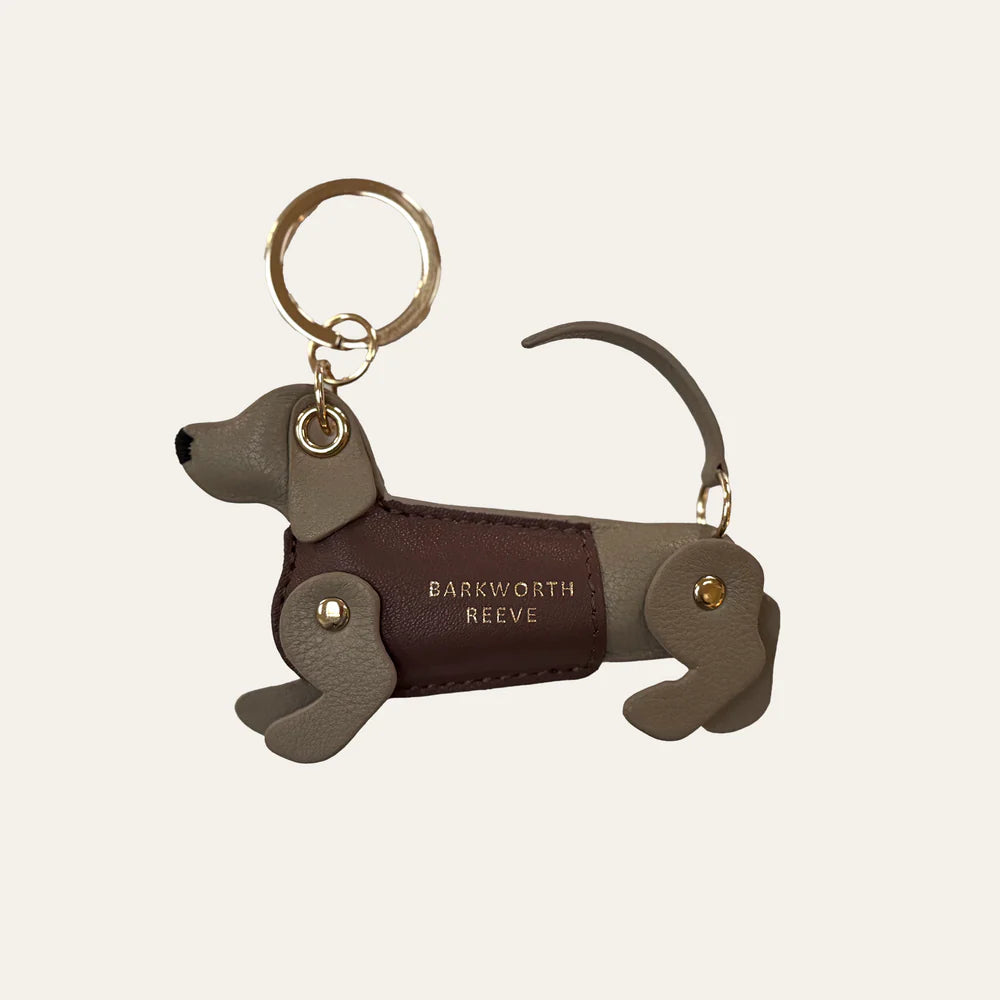 Dog-shaped keychain with 'Barkworth Reeve' branding on a beige background