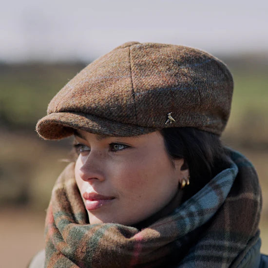 Woman wearing a brown checkered cap and plaid scarf outdoors