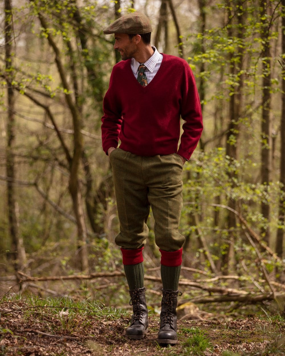 Man in a red sweater and green pants walking through a forest