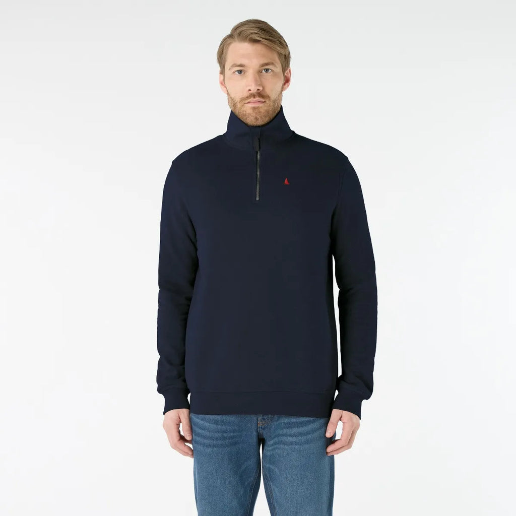 Man wearing a navy blue pullover with a small red logo on a white background