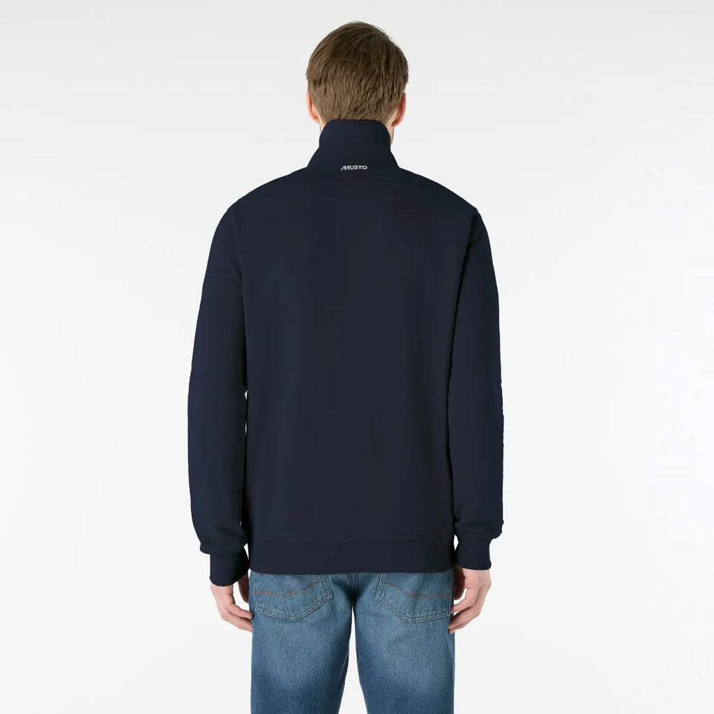 Man wearing a navy blue jacket with a brand logo on the back against a white background