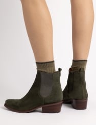 Green ankle boots worn with beige socks on a white background