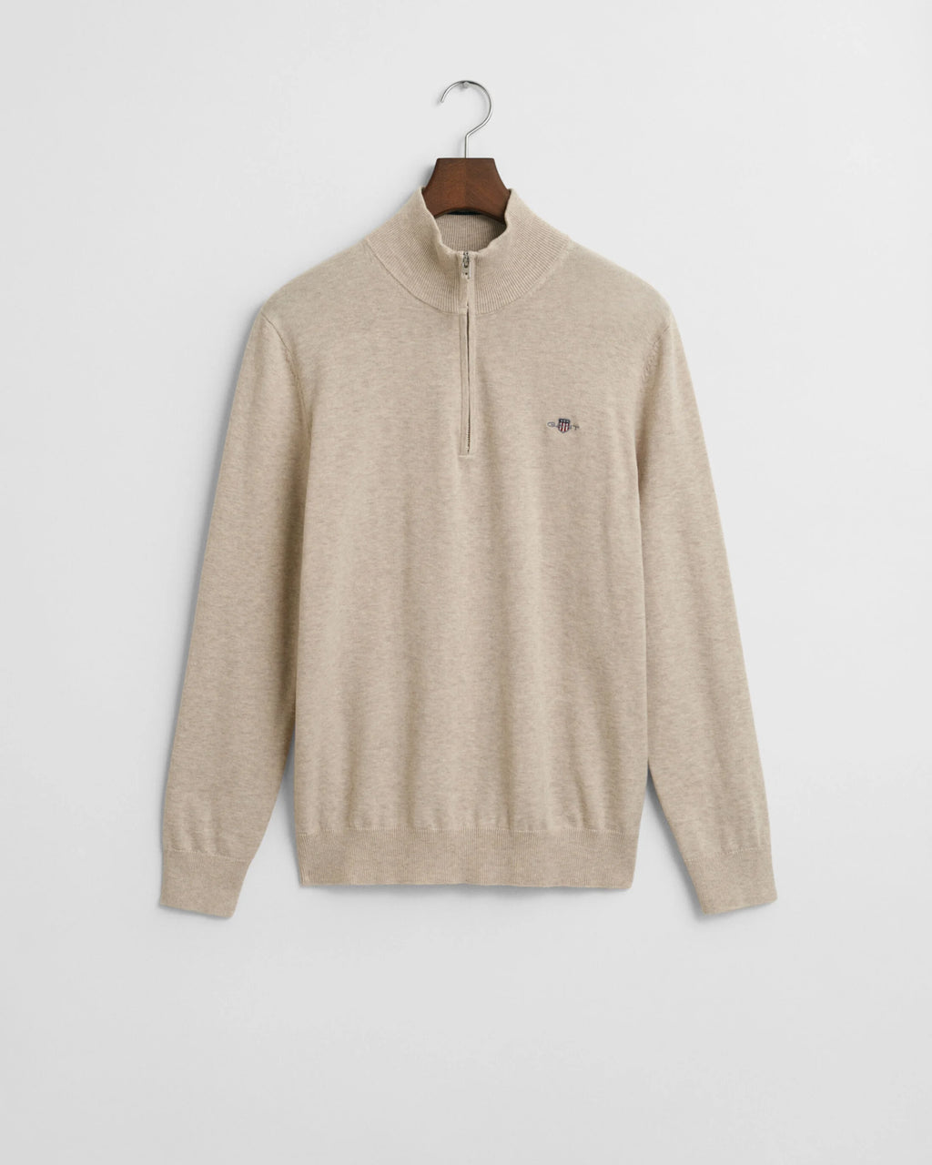Beige sweater on a hanger against a light gray background