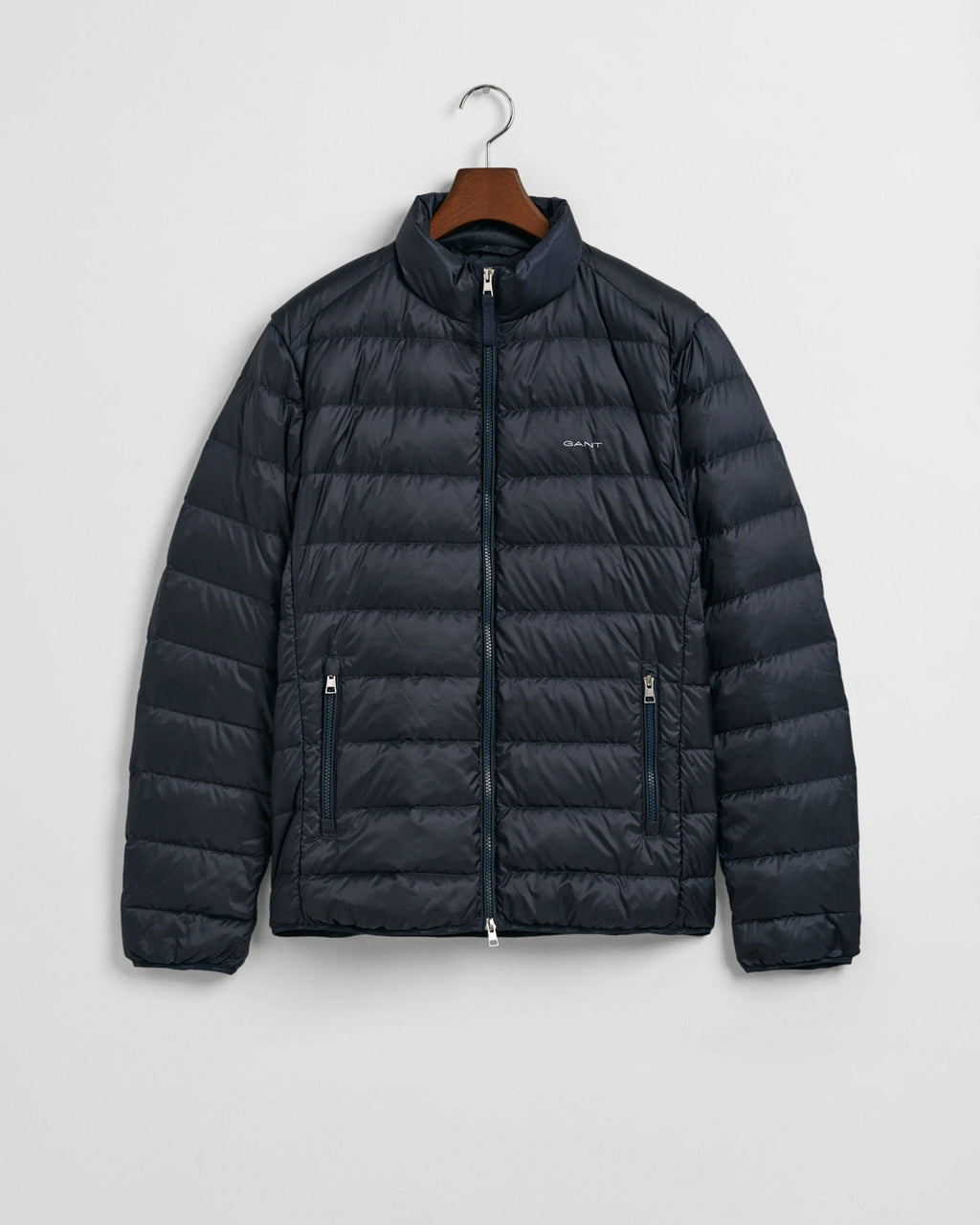 Dark blue puffer jacket on a hanger against a light gray background