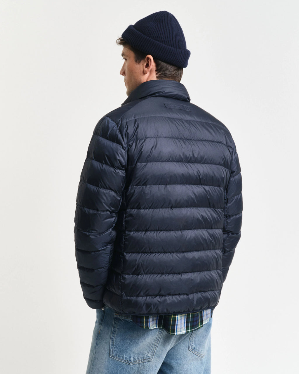 Man wearing a navy puffer jacket and beanie on a light gray background