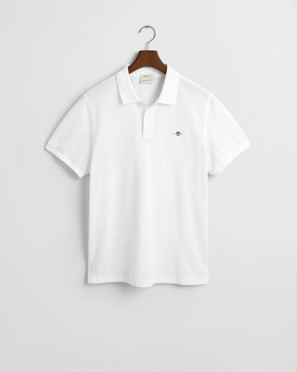 White polo shirt on a hanger against a light gray background