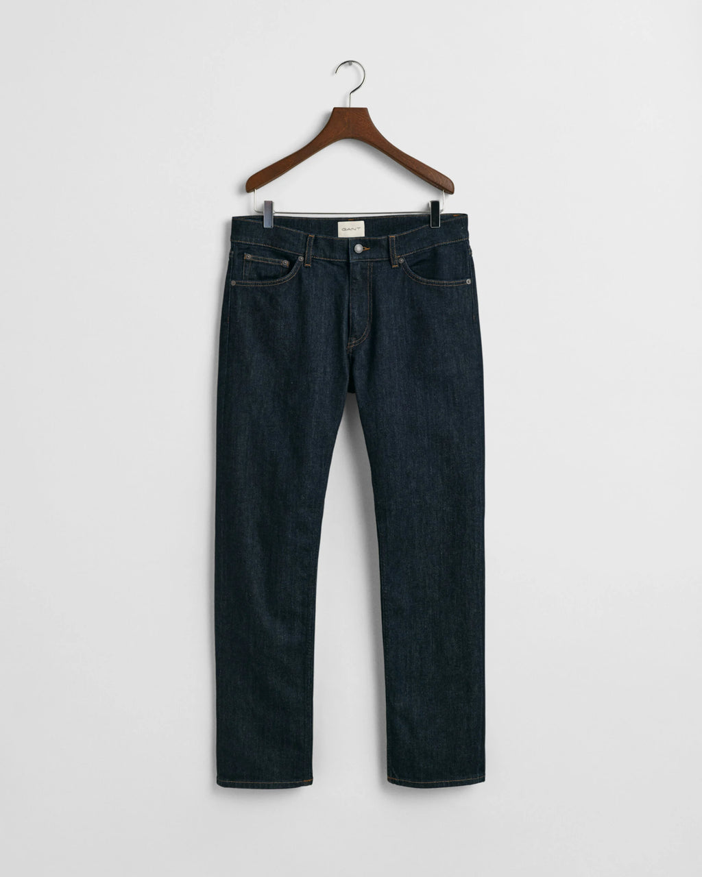 Dark blue jeans on a hanger against a white background