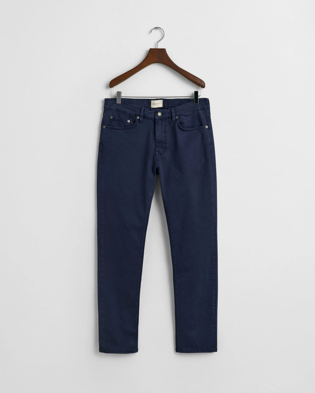 Navy blue jeans on a hanger against a white background