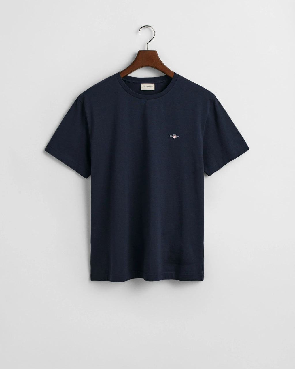 Navy blue t-shirt on a wooden hanger against a light gray background