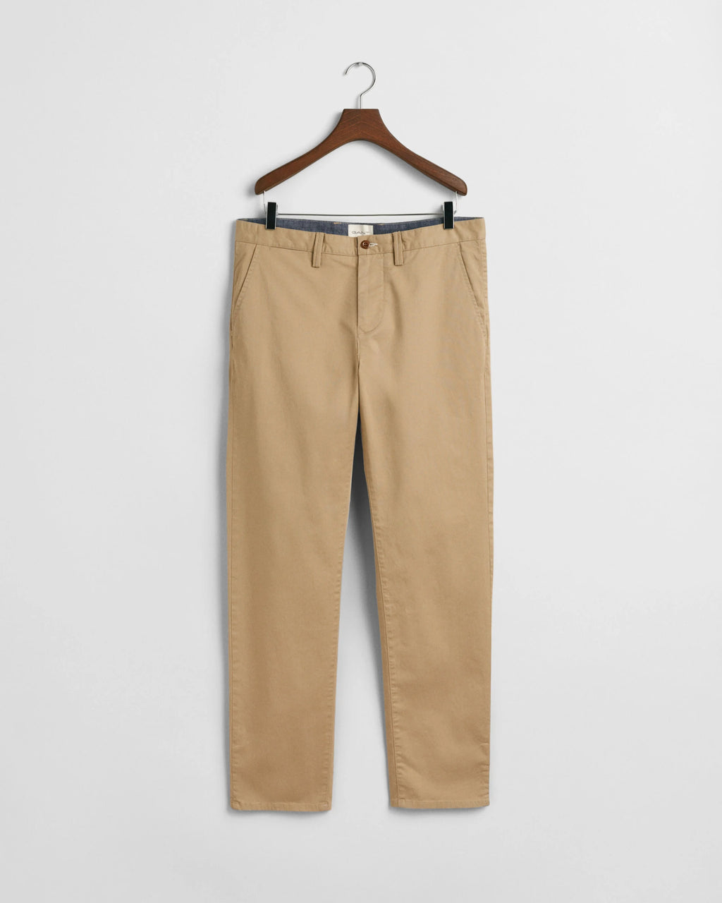 Beige pants on a hanger against a white background