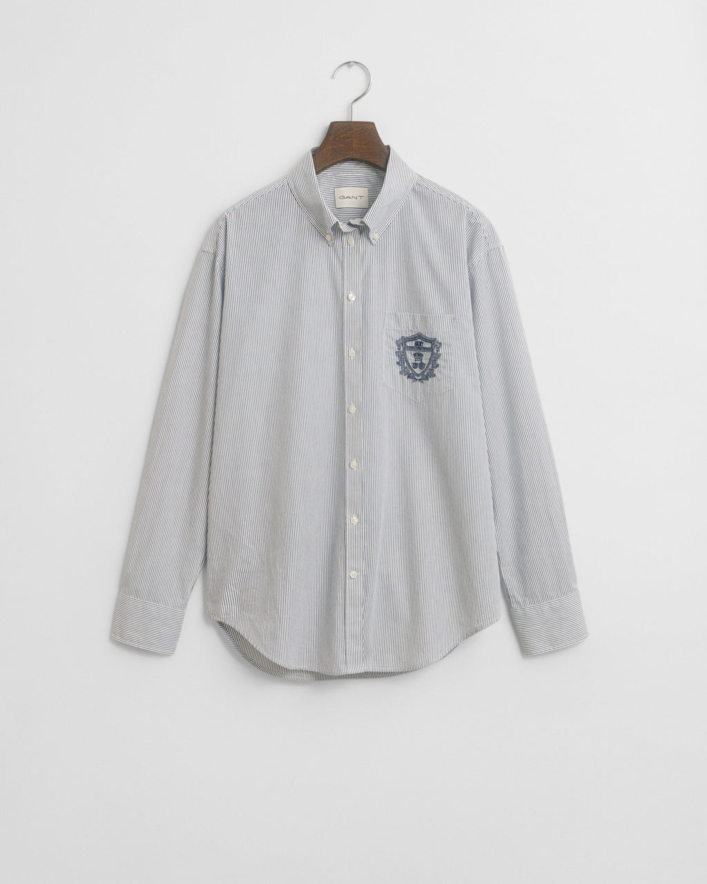 Gray button-up shirt with a logo on a hanger against a light gray background