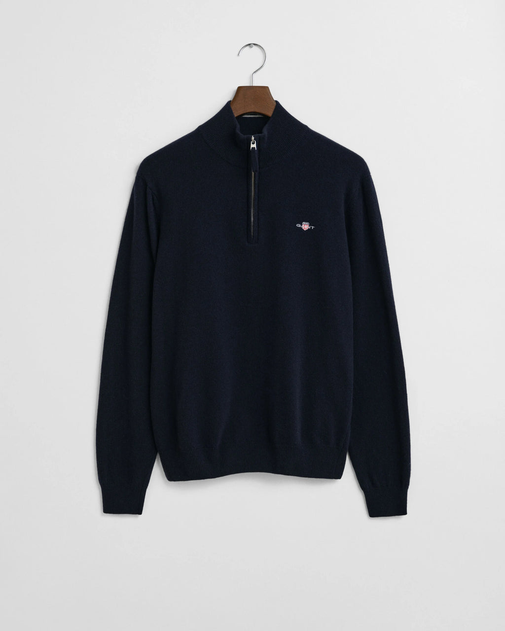 Navy blue sweater with a small logo on a hanger against a light gray background