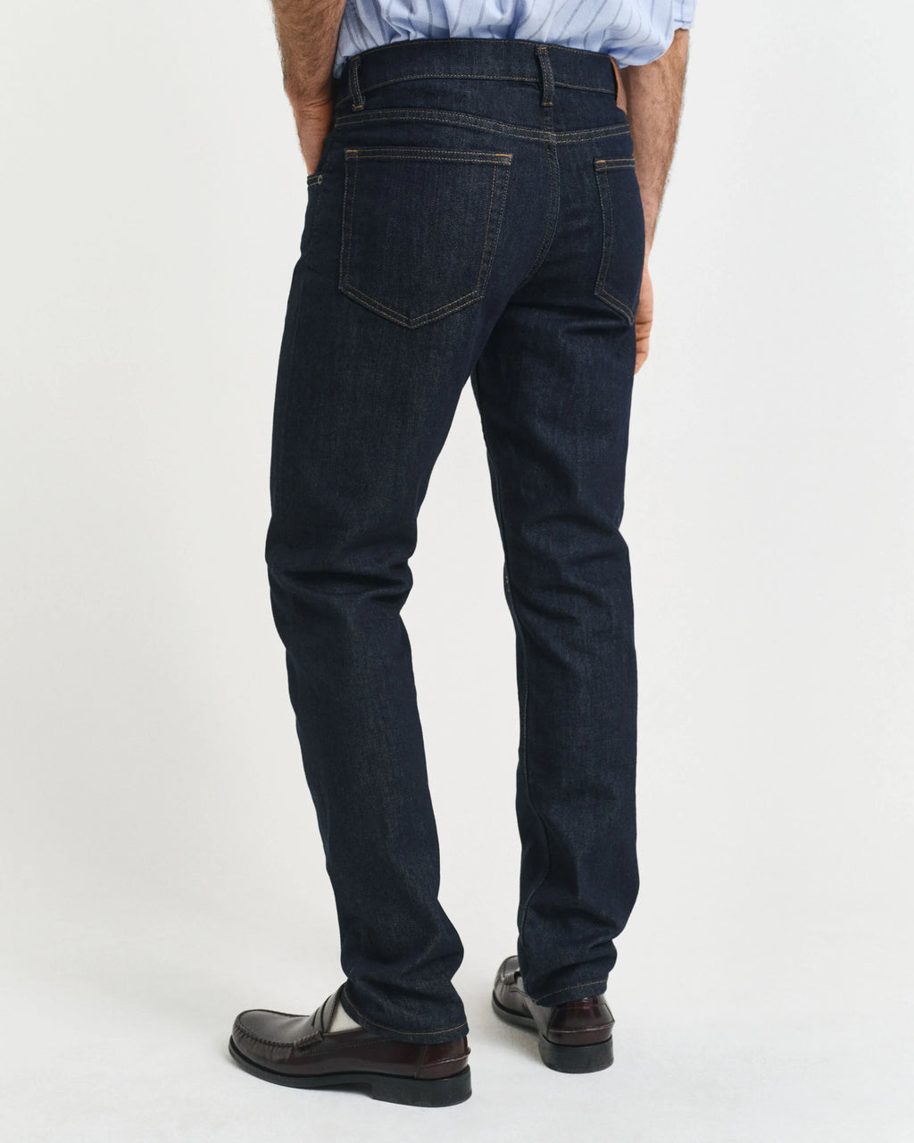 Person wearing dark blue jeans on a white background