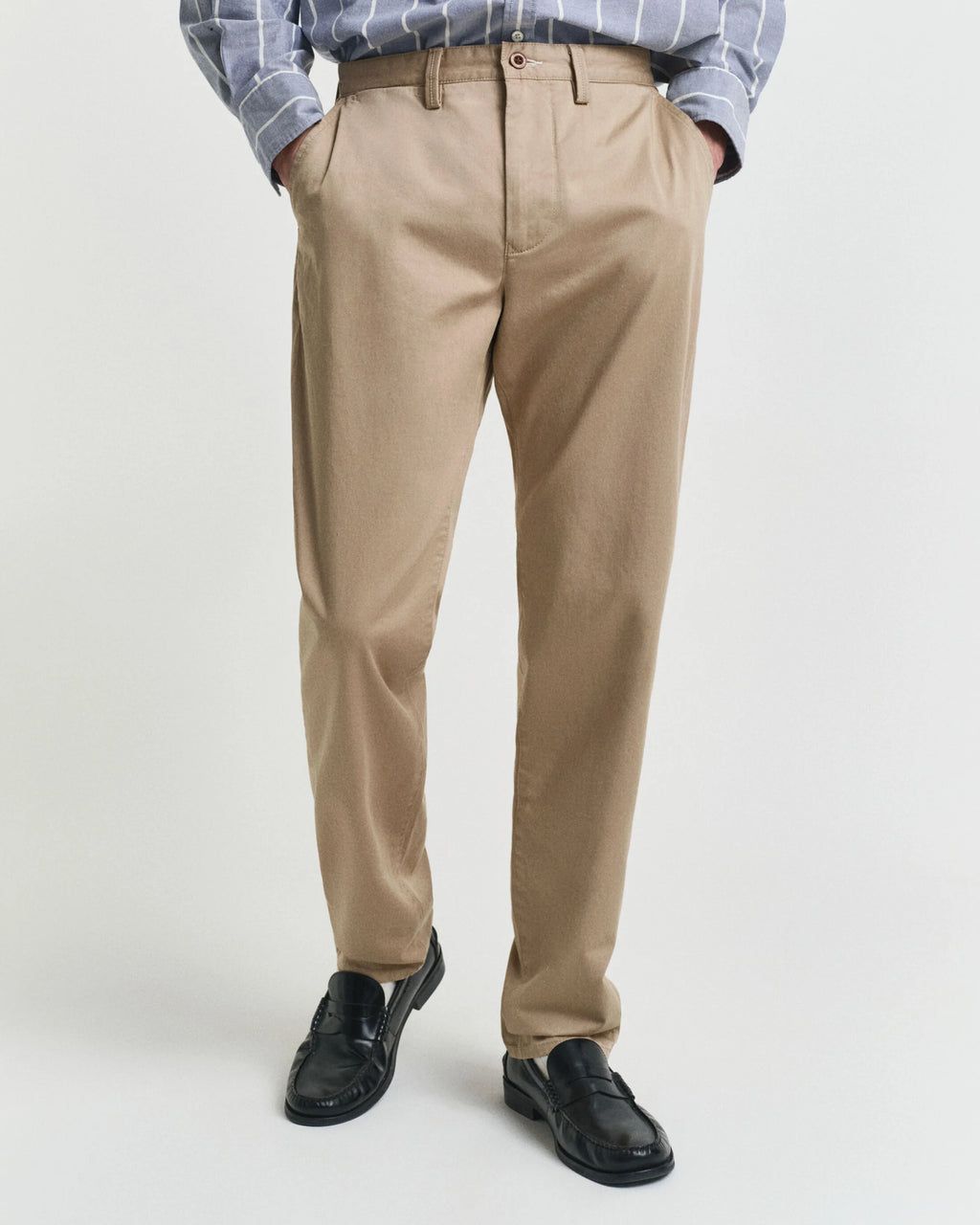 Person wearing beige pants with a plain background