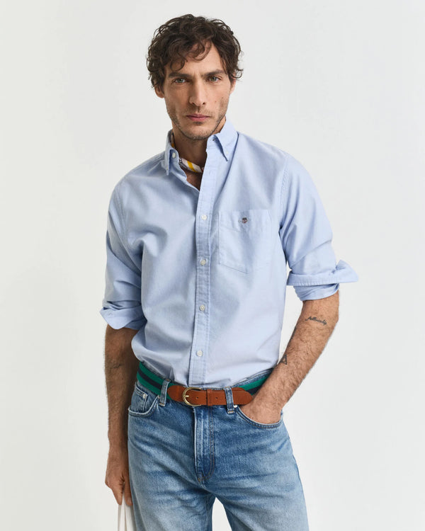 Man wearing a light blue shirt and jeans on a white background